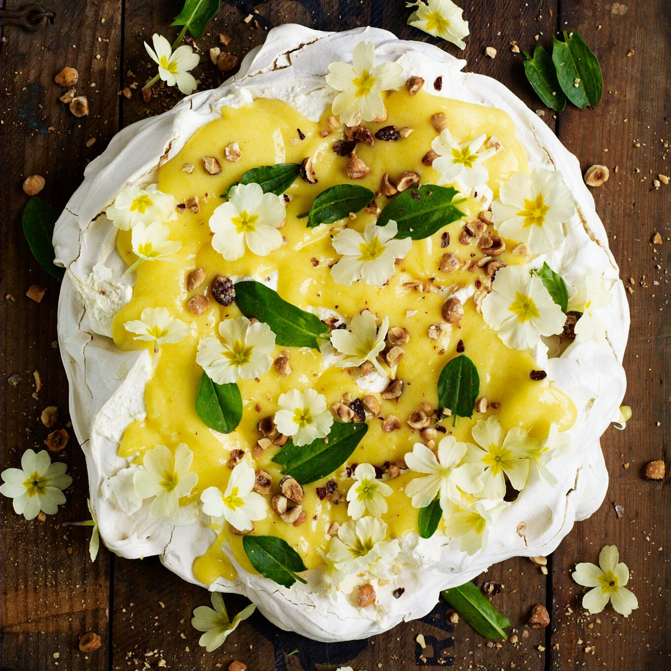 Meringue with lemon curd, cream, hazelnuts, primroses and sorrel