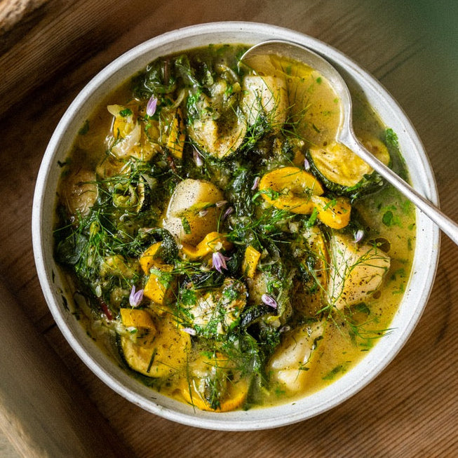 A bowl of courgette and new potato soup with fresh herbs
