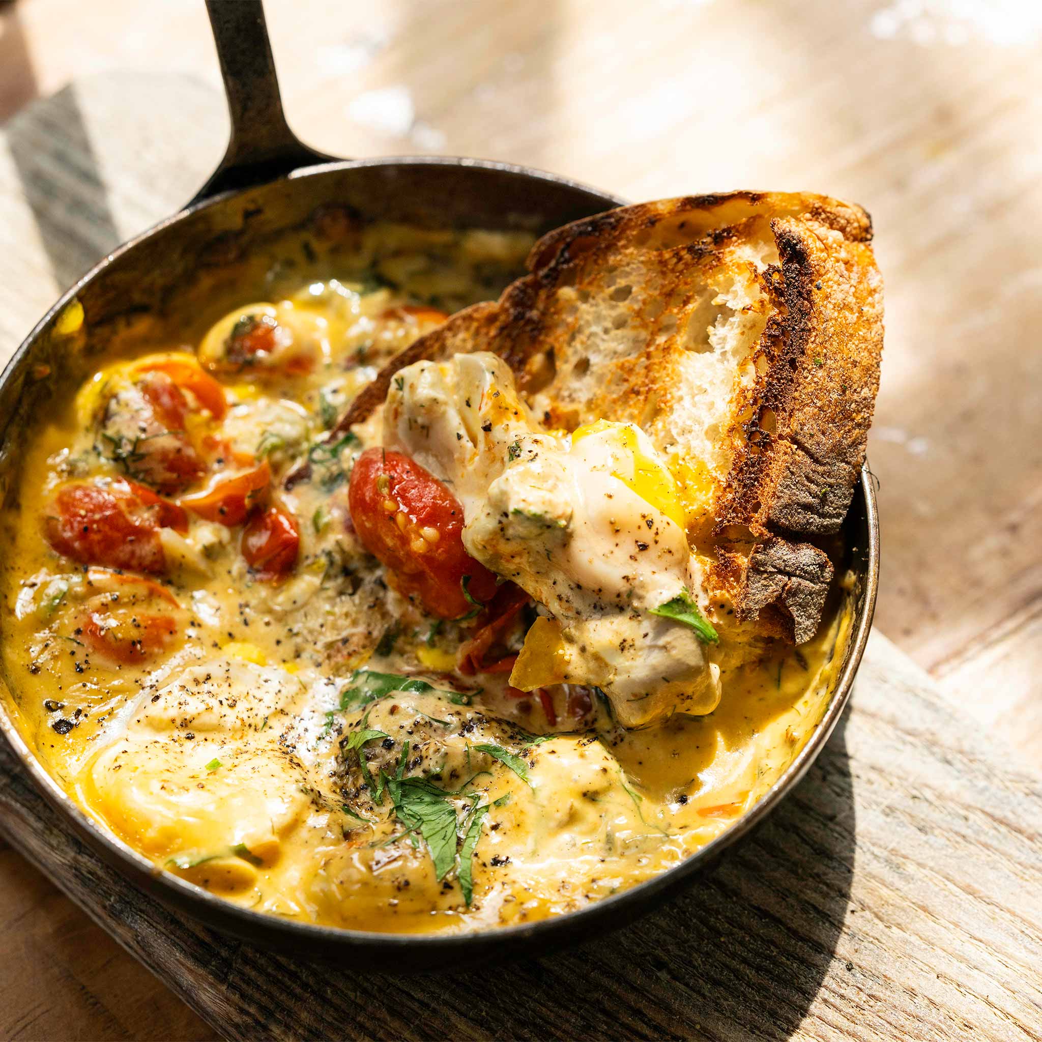 Early summer baked eggs with tomatoes, garlic, fennel seeds and lovage