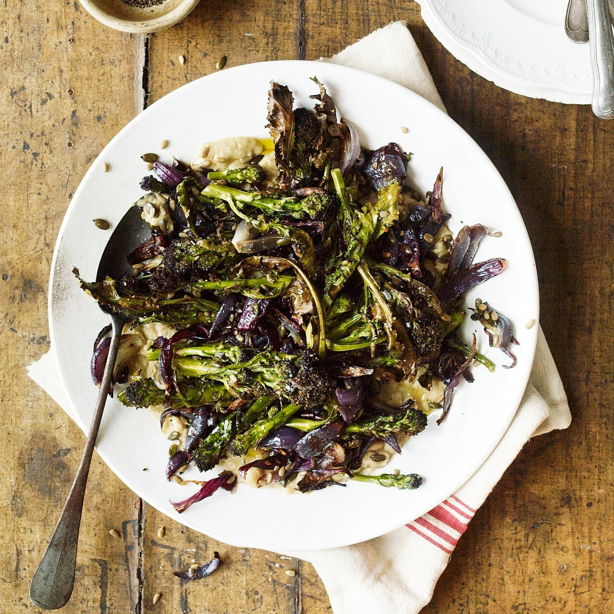 Roast purple sprouting broccoli with smashed white beans, rosemary, onions, chilli and toasted seeds