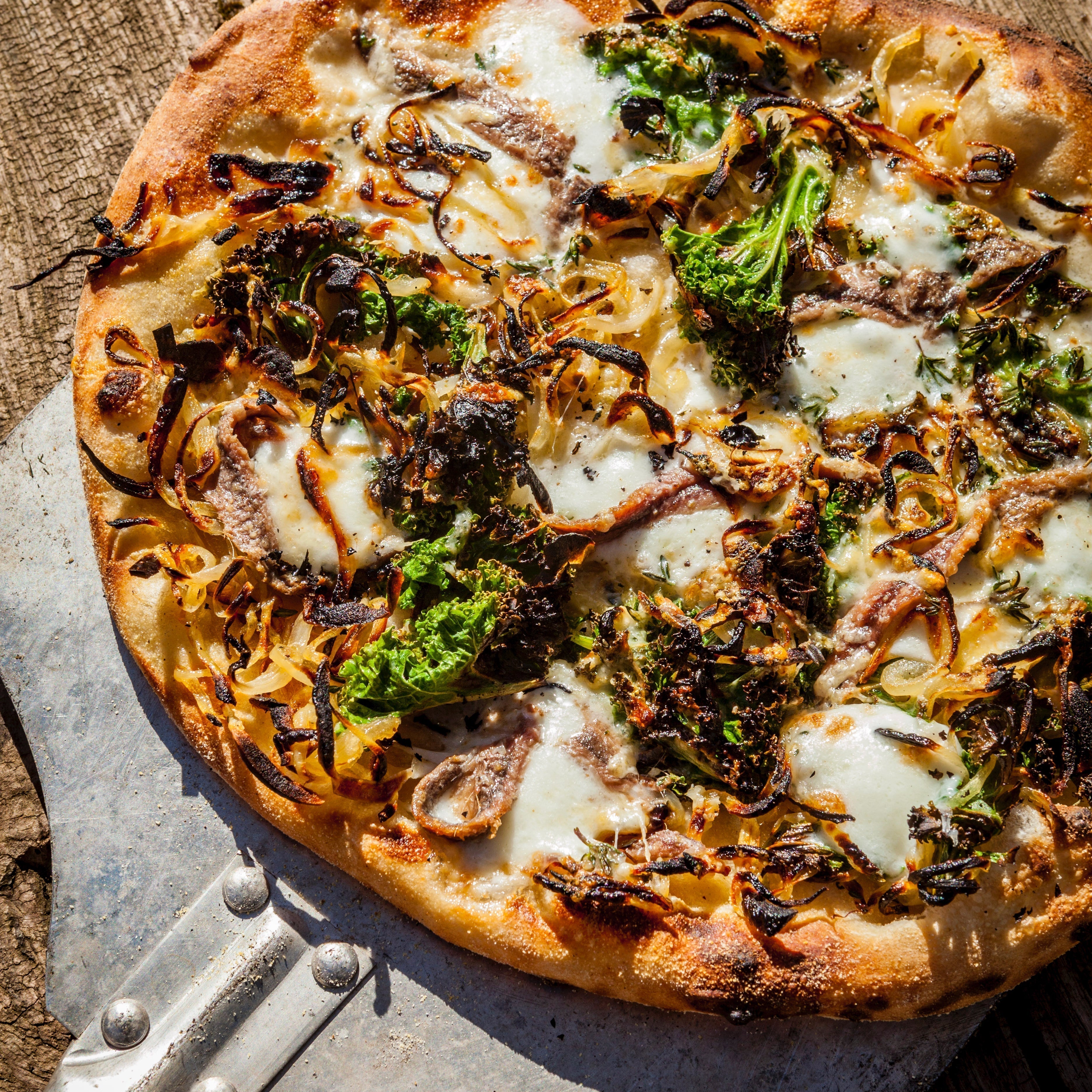 Onion and kale pizza with mozzarella and anchovies