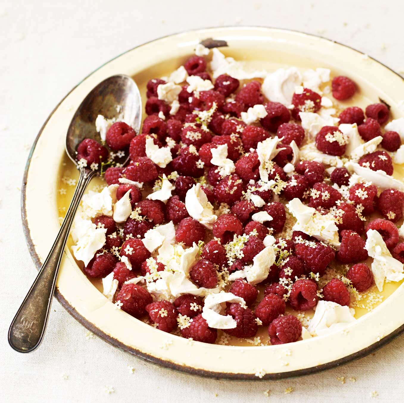 Raspberries in elderflower syrup with crushed meringue & elderflower petals